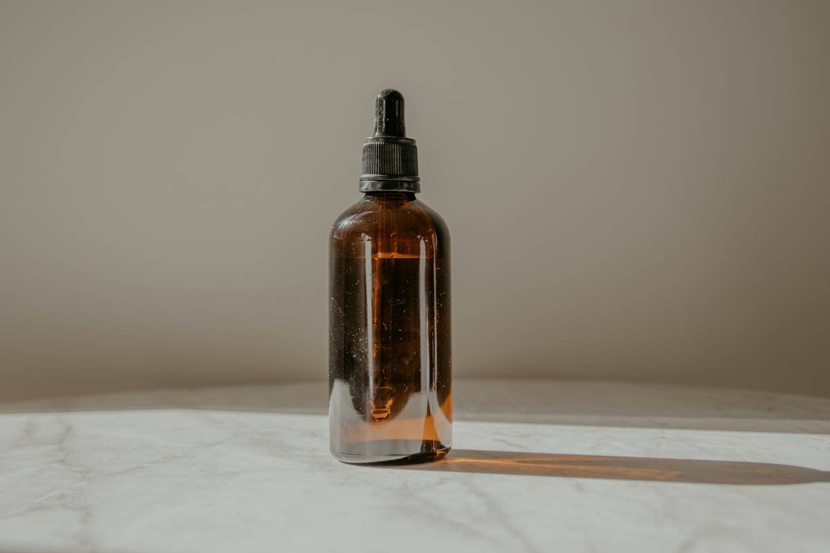Bottle of herbal balancing toner with fresh neem leaves and chamomile flowers